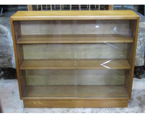 A light oak floorstanding bookcase enclosed by a pair of sliding glass doors revealing two adjustable shelves to interior ove