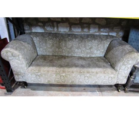 A Victorian Chesterfield sofa with floral patterned upholstery on a beige ground and rolled drop arms raised on turned forele