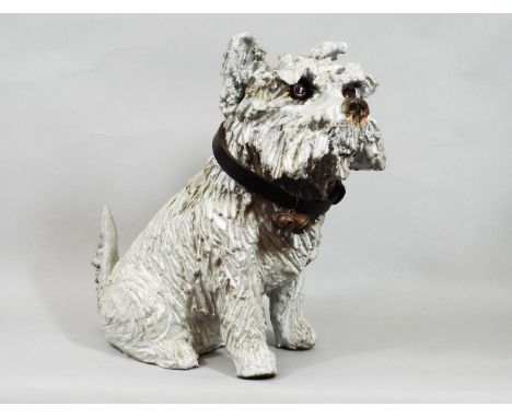 A ceramic figure of a terrier with glass eyes with attached vintage leather collar, 30 cm in height