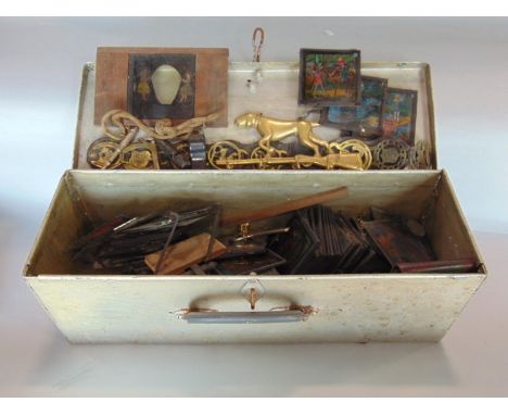 A tin trunk containing a mixture of interesting items mainly magic lanterns, light, horses brasses and others 
