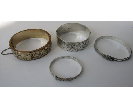 Four decorative bangles comprising a silver hinged example with engraved scrolled decoration, a similar rolled gold example, 