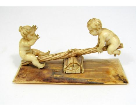 19th century ivory carving - two naked children seated on a rustic see saw, 14cm long 