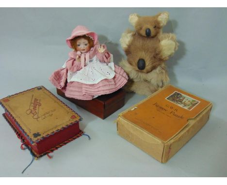 A box containing mixed items to include a G.W.R. jigsaw puzzle, a box containing bridge counters, a china doll and a koala be