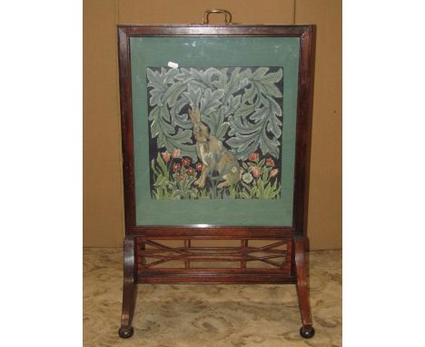 An Edwardian mahogany firescreen with moulded frame, swept supports and pierced fretwork detail, enclosing a glazed tapestry 