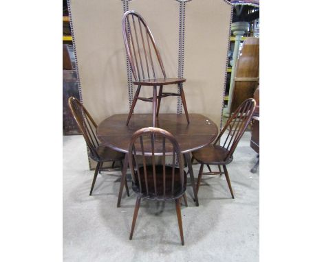 An Ercol dark stained elm and beechwood oval drop leaf kitchen table raised on splayed square tapered supports together with 