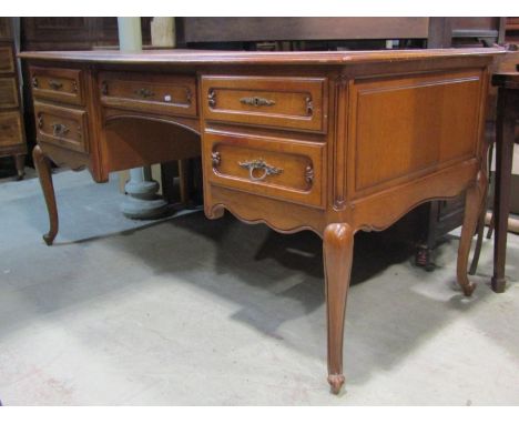 A medium to light oak knee-hole desk in the Louis XV style with moulded outline over an arrangement of five frieze drawers wi