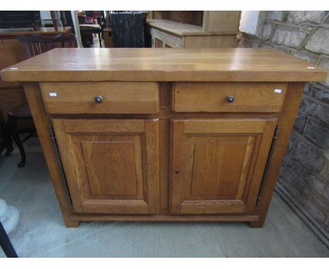 A good quality contemporary John Lewis light oak side cupboard enclosed by a pair of moulded fielded panelled doors beneath t