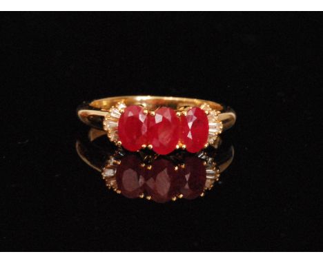 An 18ct hallmarked ruby and diamond ring, three oval cut claw set rubies flanked by five tapering baguette to each shoulder, 