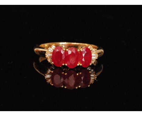 An 18ct hallmarked ruby and diamond ring, three oval cut claw set rubies flanked by five tapering baguette to each shoulder, 