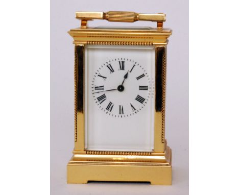 An early 20th Century brass carriage clock with white painted enamelled dial in beaded edged case on stepped bracket plinth, 