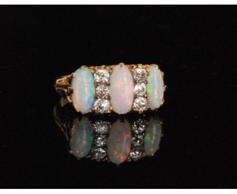 An opal and diamond ring, the central oval cabochon opal flanked by two smaller opals and spaced by six rose cut diamonds, cl