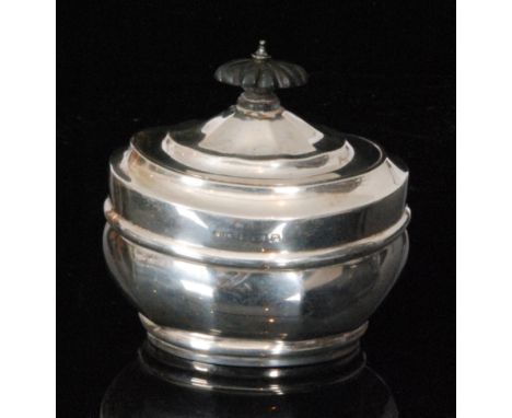 An Edwardian hallmarked silver boat shaped tea caddy of plain form, hinged cover terminating in ebonised finial, Birmingham 1