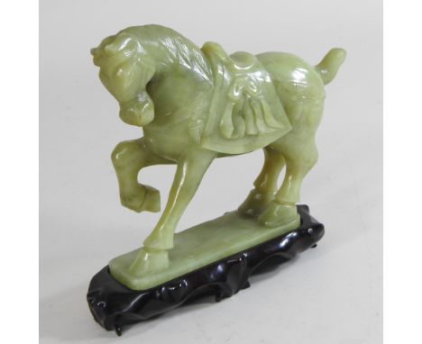 A jade coloured hardstone model of a horse, mounted on a wooden plinth, 17cm high