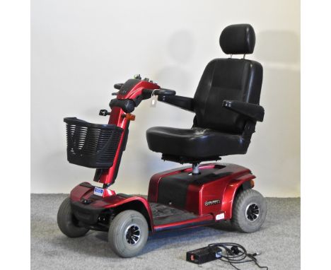 A red Celebrity Deluxe mobility scooter, with charger