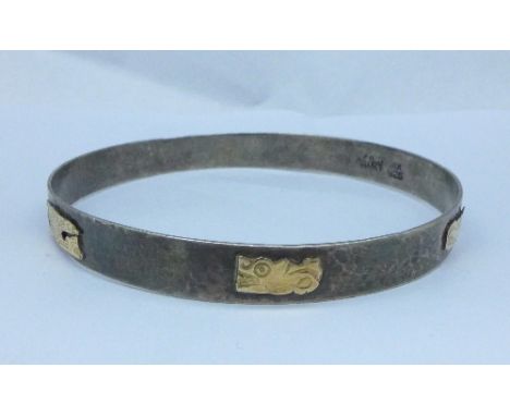 A hammered silver bangle with gold applied decoration