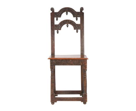 An unusual Charles II oak backstool, circa 1665The back of two arch-shaped narrow splats, carved with stylised foliage and wi