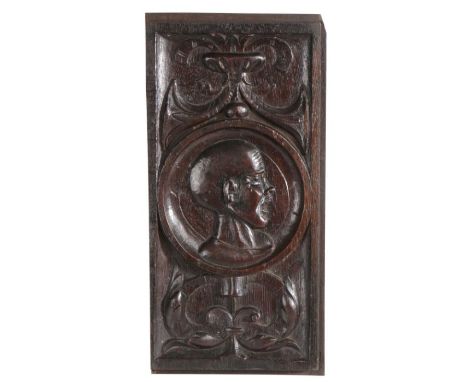 An unusual Henry VIII carved oak Romayne-type panel, circa 1530-40Centred with the carved portrait of a bald 'angry' male, fu