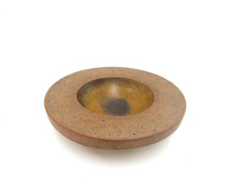 ROBIN WELCH (1936-2019) A studio stoneware dish, central scoop hollow with ochre glaze. Impressed seal. 20.5cm diameter x 5cm