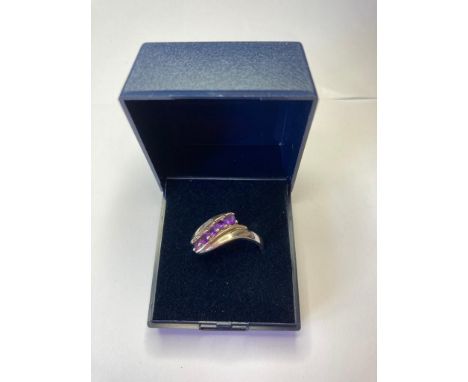 Silver ring having five stones the colour of dark amethyst to top in crossover style. 