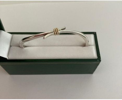 Silver bangle in modernist crossover form having three golden contrasting hoops to top. Full silver hallmark. Presented in je