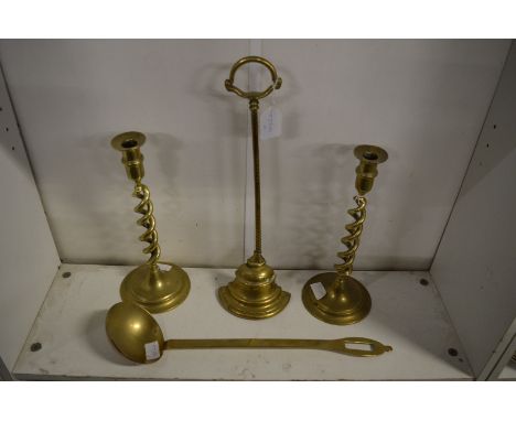 A brass door stop, pair of brass candlesticks and a ladle.