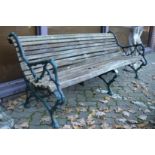 A large garden bench with wooden slats and cast iron supports.
