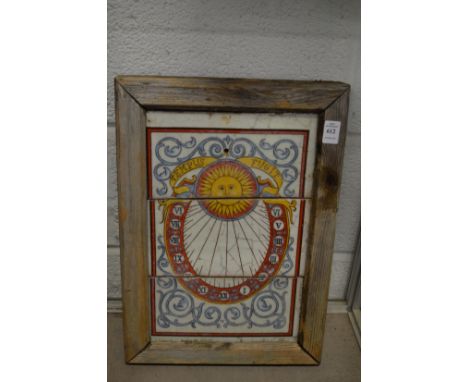 A tile plaque depicting a sundial, framed.