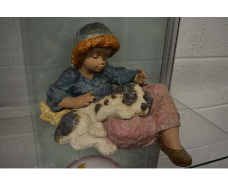 A large Lladro pottery model of a young child seated with a puppy on its lap.
