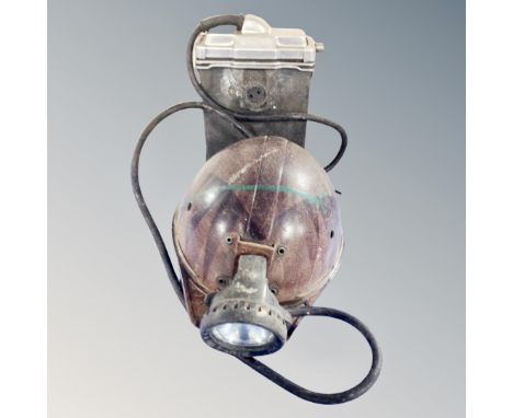 A vintage coal miner's helmet with lamp and battery pack