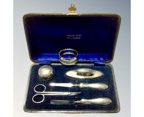 A four piece cased silver-handled manicure set together with a further pair of nail scissors in case, together with silver na