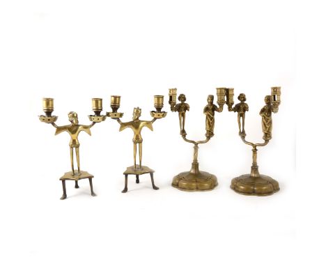 Two pairs of cast brass Neo-Gothic style figural twin-light candlestands, one pair cast with a male and female figure to each