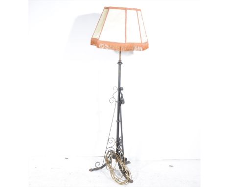 An Edwardian metal standard lamp, rolled triform base, with part velum shade, as assembled 165cm.