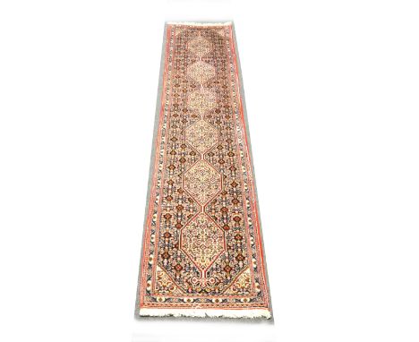 A Hamadan pattern runner, with six medallions joined by a pol, enclosed by spandrels and borders, 294cm x 52cm.