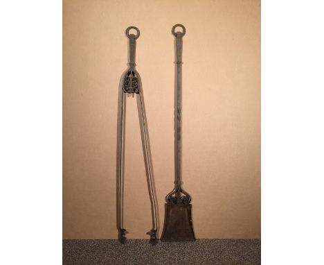A pair of particularly large Cotswold School wrought iron fire tools, comprising shovel and tongs, each with scroll work deco