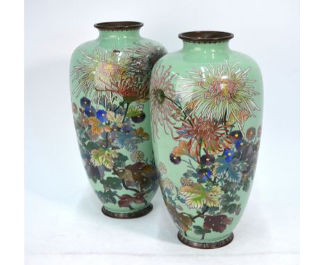 A pair of Japanese cloisonne enamel vases; each one decorated with a bold floral design on the pale almond-green ground. Both