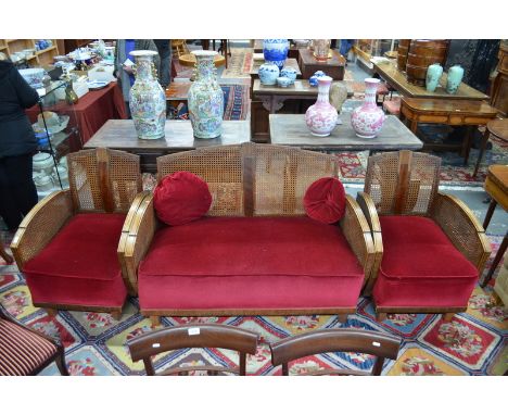 An Art Deco period walnut framed three-piece bergere suite with red velveteen seats, raised on black feet comprising a two se