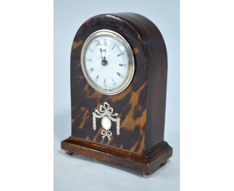 An Edwardian part tortoiseshell dome cased bedside/mantel clock, the white enamelled dial with a hall-marked silver bezel and