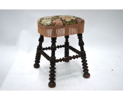 An antique turned fruitwood stool, the four bobbin turned legs united by conforming all-round stretchers, the seat later fabr
