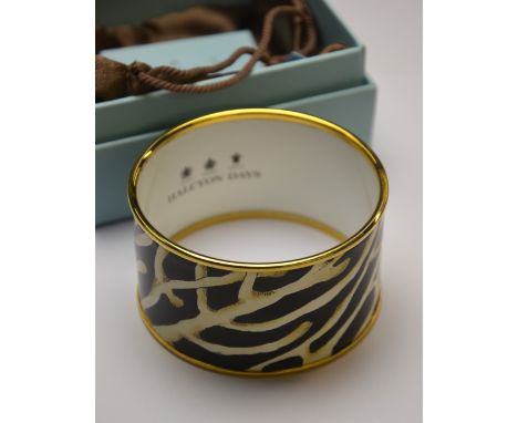 A Halcyon Days gilt metal and cream and black organic design enamel bangle, 4 cm x 6.7 cm diam, in box with pouch and paperwo