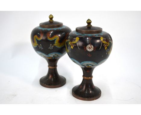A pair of Chinese Cloisonne enamel vases; each one with cover and knop finial, decorated with dragons confronting a flaming p
