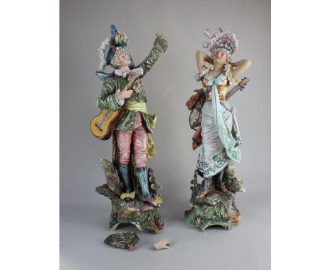 A pair of Majolica figures of musicians, the man with a feathered hat and guitar, the woman with a lute (a/f) 58cm high