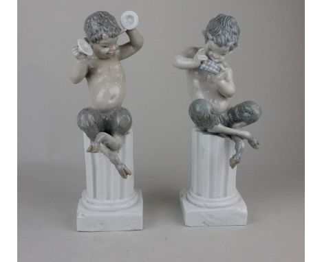 A pair of Lladro porcelain satyr / faun figures playing musical instruments and seated atop columns 27cm high