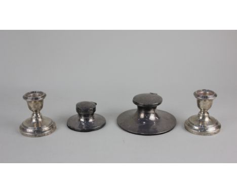 An early 20th century silver capstan inkwell another smaller inkwell and a pair of George V silver dwarf candlesticks, all on