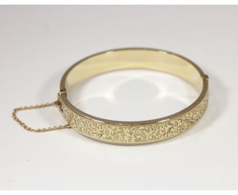 A 9ct gold hinged bangle with engraved decoration, 12g