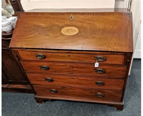 An Edwardian mahogany bureau the fall front with central inlaid oval shell enclosing fitted interior above four graduated dra