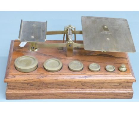 Victorian brass postage scales on oak base with weights from 8oz to 1/2oz, width 29cm