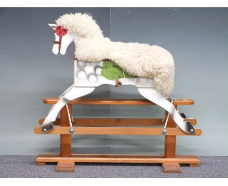 A wooden rocking horse painted in dapple grey with wool seat covering on rocker base with remnants of original maker's label,