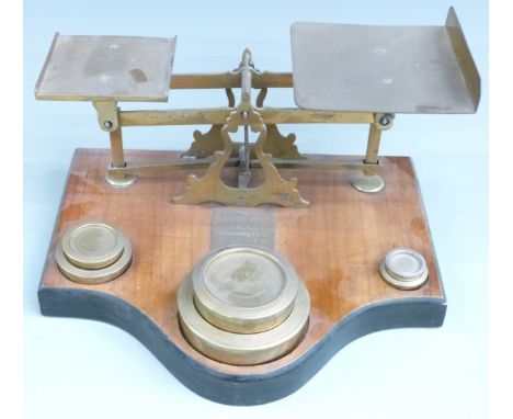 Victorian brass parcel scales on wooden base with flat stacking weights from 4lb down to 2oz, width 37cm