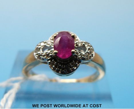 A 9ct gold ring set with an oval ruby surrounded by diamonds (size M/N) 