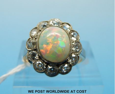 A white metal ring set with an oval opal surrounded by diamonds (size M)